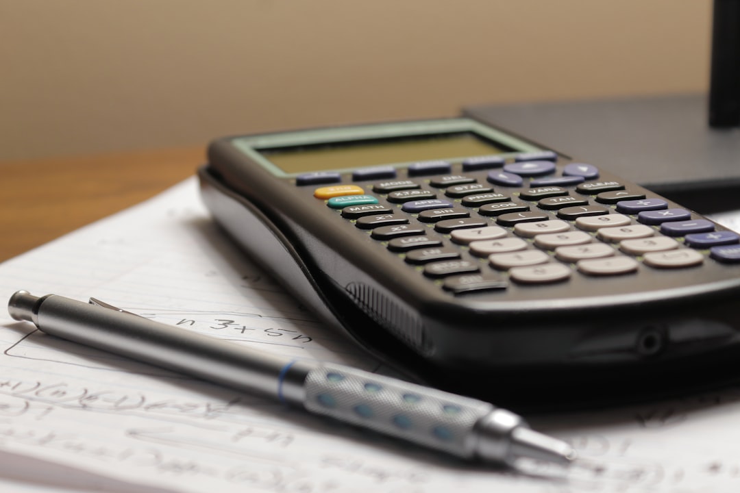 a calculator and pen resting on a sheet of annotated paper