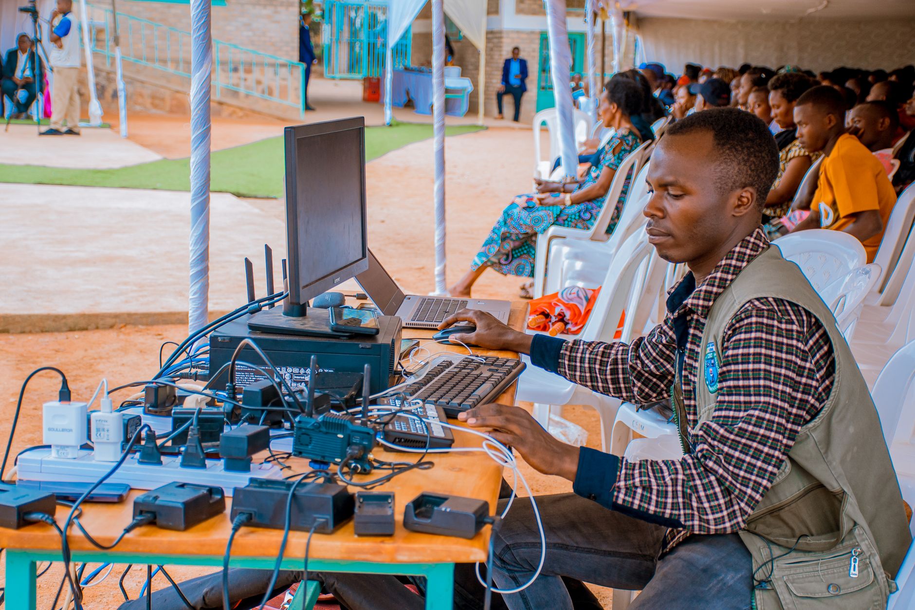 Technician managing electrical and computer setup at an outdoor event with attentive audience. — Best Japanese Language Learn