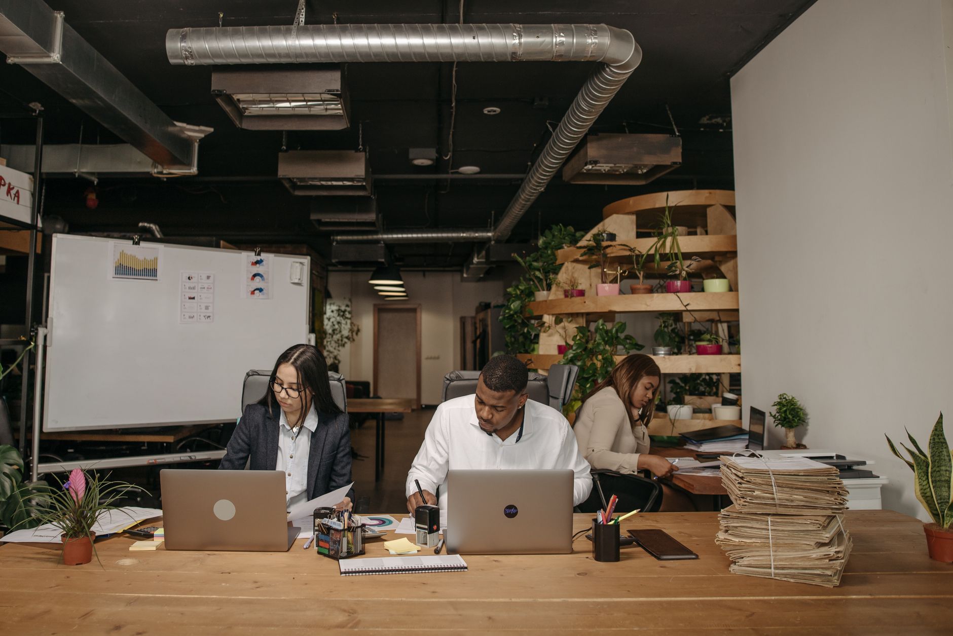 Three professionals focused on work in a stylish office with laptops and documents. — Get the Full Story on Local Issues with