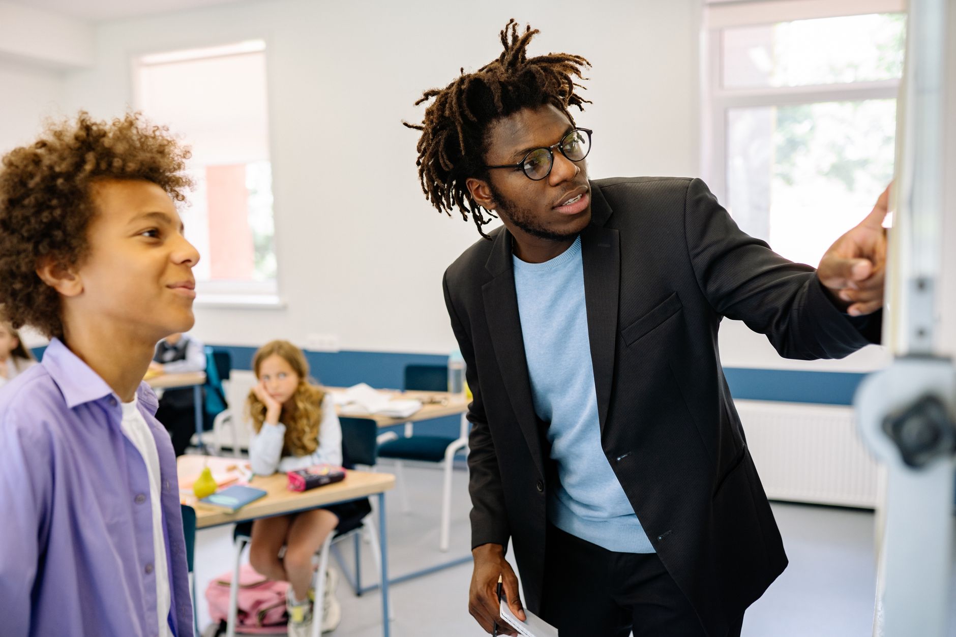 Teacher guiding a student in a classroom, promoting interactive learning. — IB Economics - Expert Tuition for Higher Level an