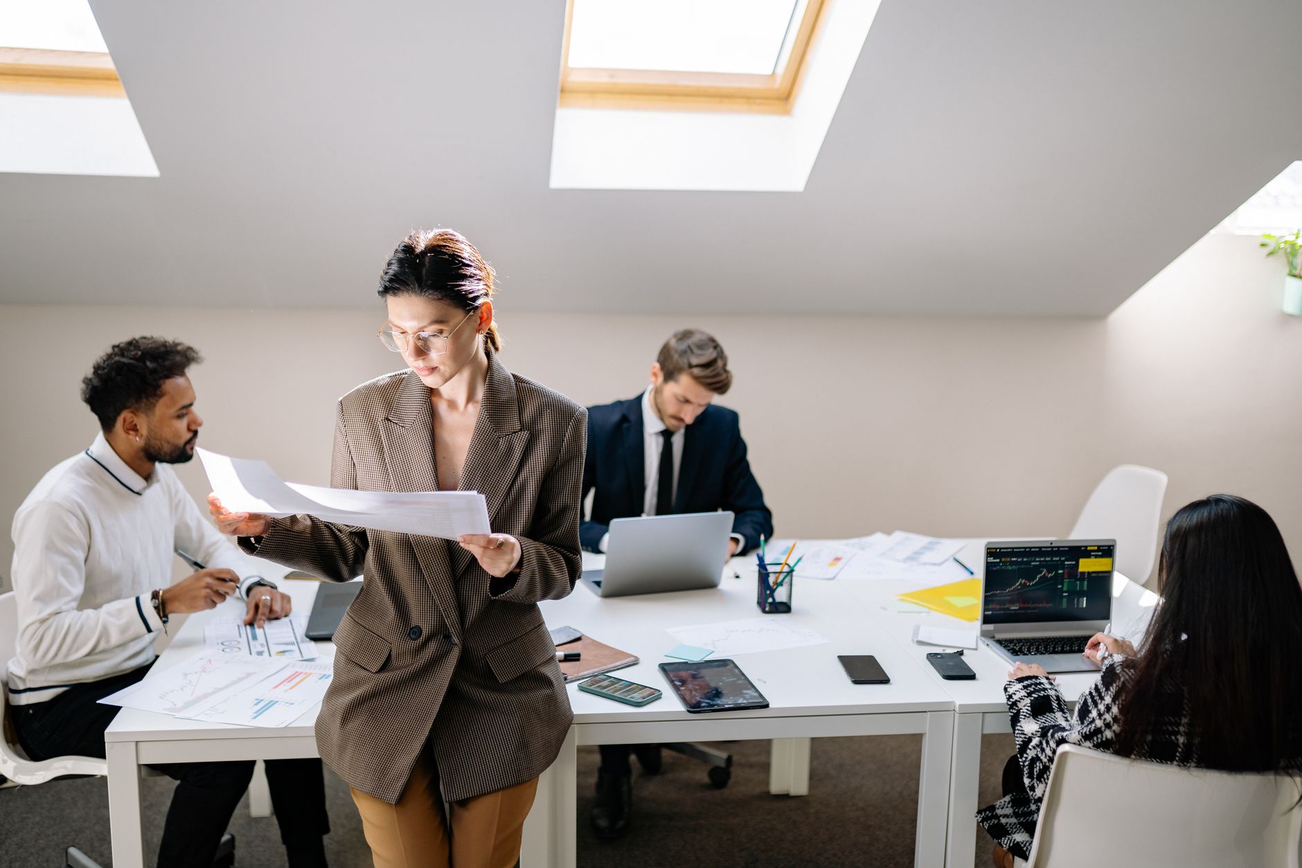 Group of colleagues working together with laptops and documents in a bright office. — IronFX Broker Review: A Comprehensive I