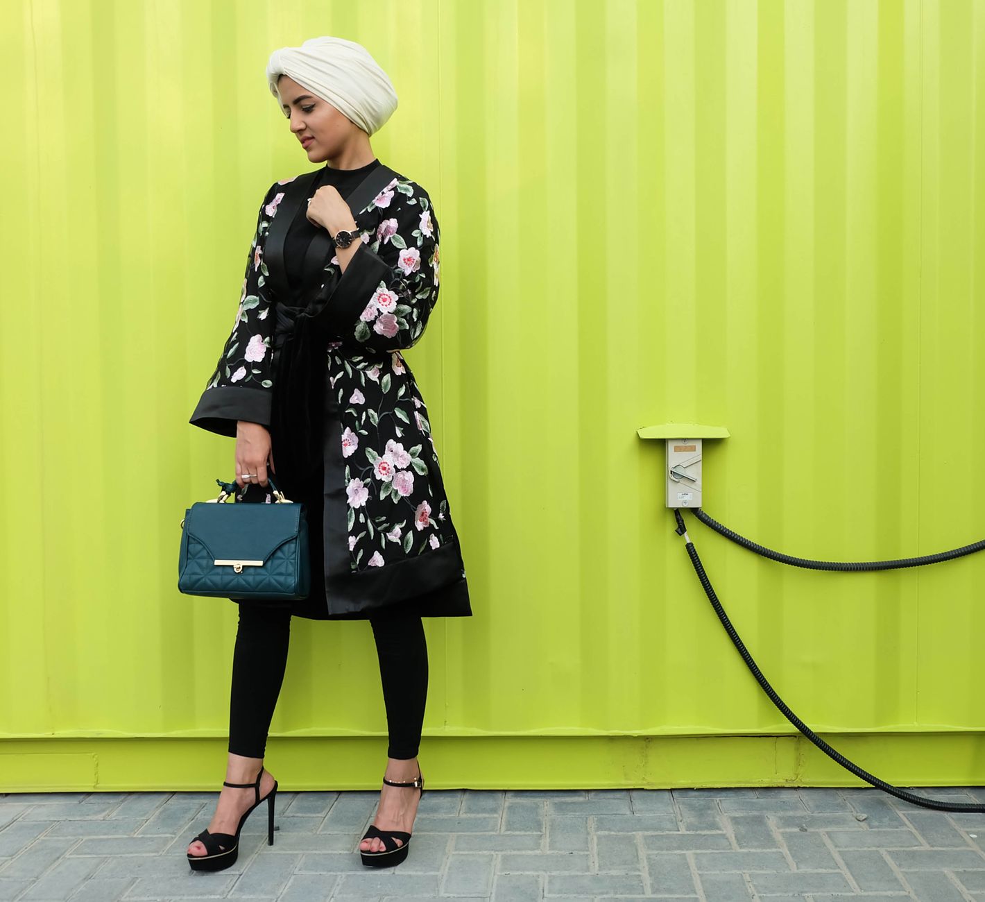 Fashionable woman in a floral coat and hijab standing with a green bag in Dubai. — The Importance of Compliance: How CBD Merc