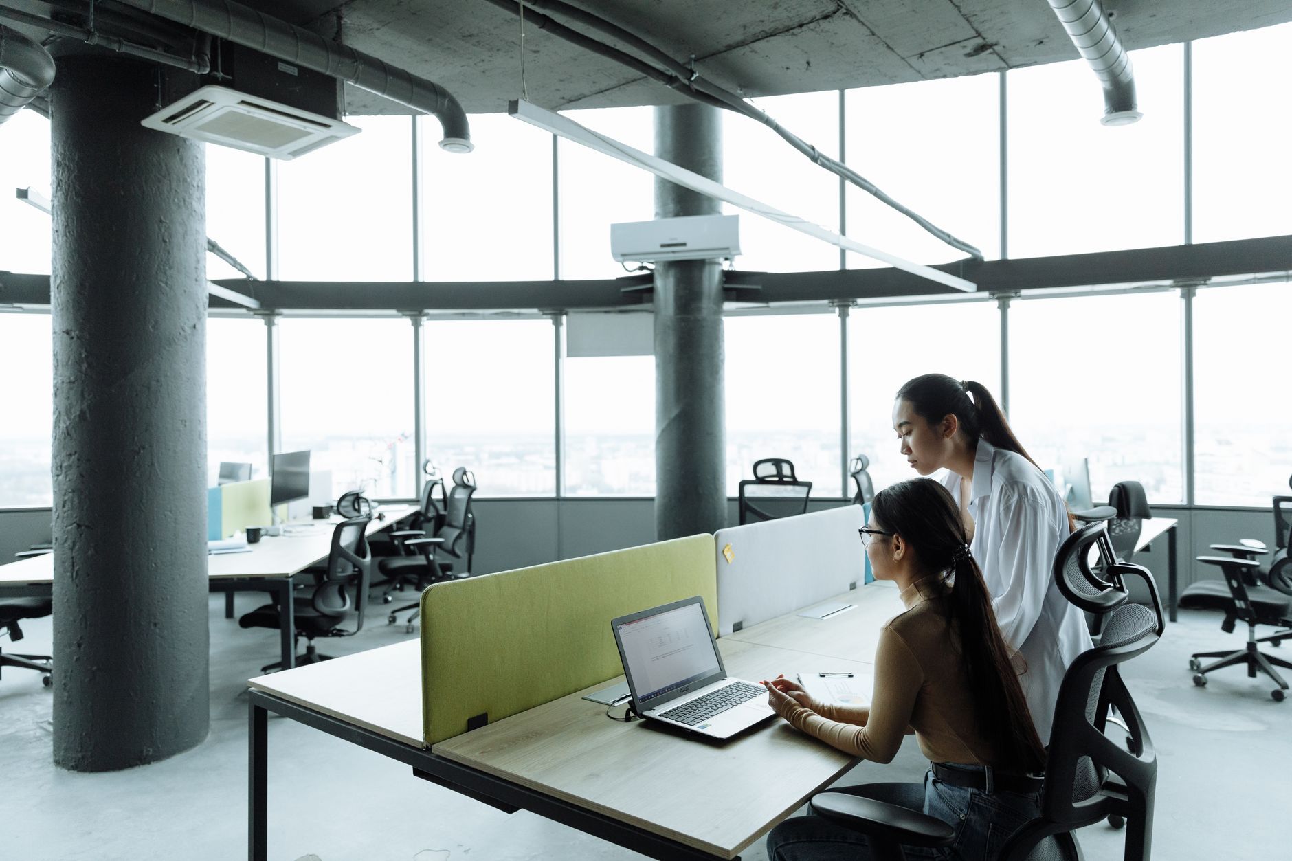 Two Asian women collaborating in a modern office environment focused on teamwork and innovation. — The Metrics of Reliability
